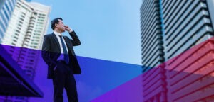 Businessman on a cellphone looking up at a skyscraper