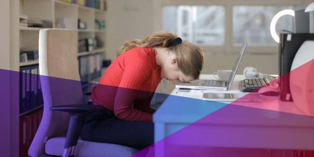 A dejected woman with her head on a desk