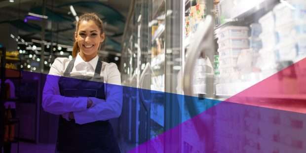 un employé de magasin souriant dans une allée d'épicerie