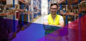 man in a safety vest with crossed arms in a warehouse